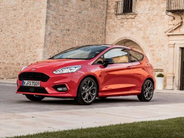 De nieuwe Ford Fiesta ST staat geparkeerd voor een stenen gebouw.