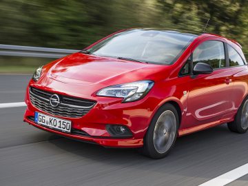 De rode Opel Corsa rijdt op een weg in Nederland.