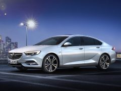 De Opel Insignia 2017 wordt 's nachts voor een stad getoond.