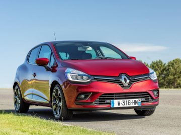 De rode Renault Clio uit 2016, een van de best verkochte auto's, rijdt over de weg.