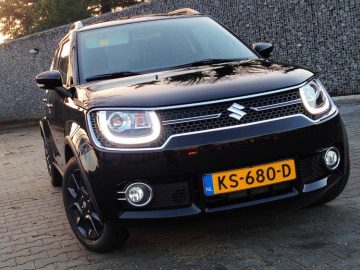 Een zwarte Suzuki Ignis stond buiten geparkeerd tijdens het gouden uur.