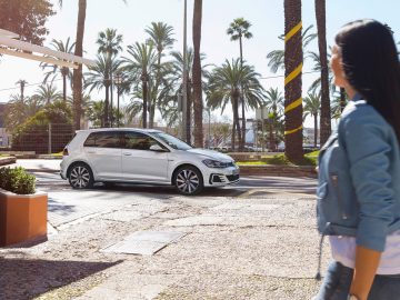 Een vrouw loopt voor een Volkswagen Golf GTI, een van de bestverkochte auto's van 2016.