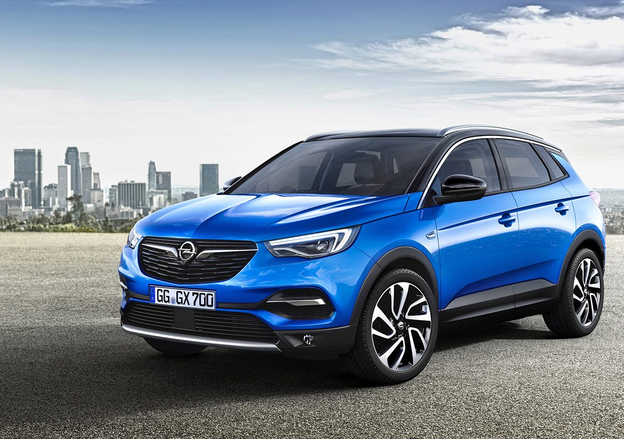 De nieuwe Opel Grandland X SUV staat geparkeerd voor een stad.