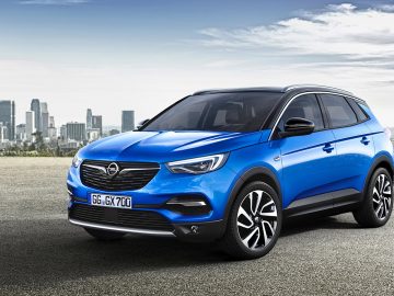 De nieuwe Opel Grandland X SUV staat geparkeerd voor een stad.