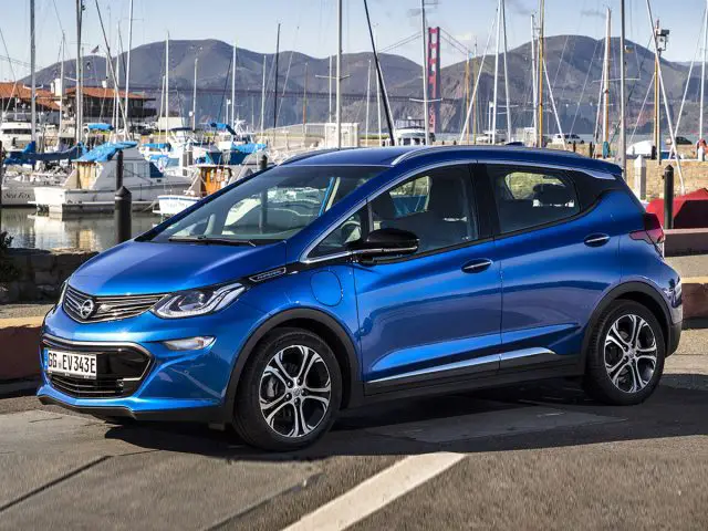 De blauwe Chevrolet Bolt #73 staat geparkeerd voor een jachthaven.