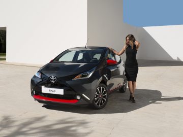 Een vrouw die naast een Toyota Aygo staat.
