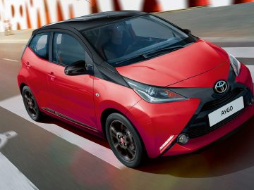 De rode Toyota Aygo rijdt over de weg naar de AutoRAI.