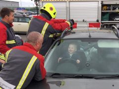 Een brandweerman is een peuter aan het sluiten in de achterbank van een auto.