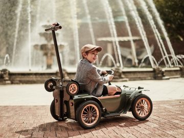 Een jongen in een elektrische loopauto van $ 3000, met een camera eraan.