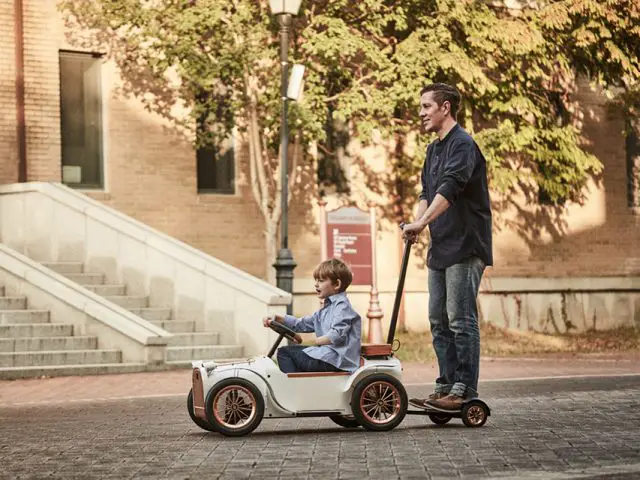 Een man en een jongen rijden op een elektrische loopauto van 3.000 dollar.