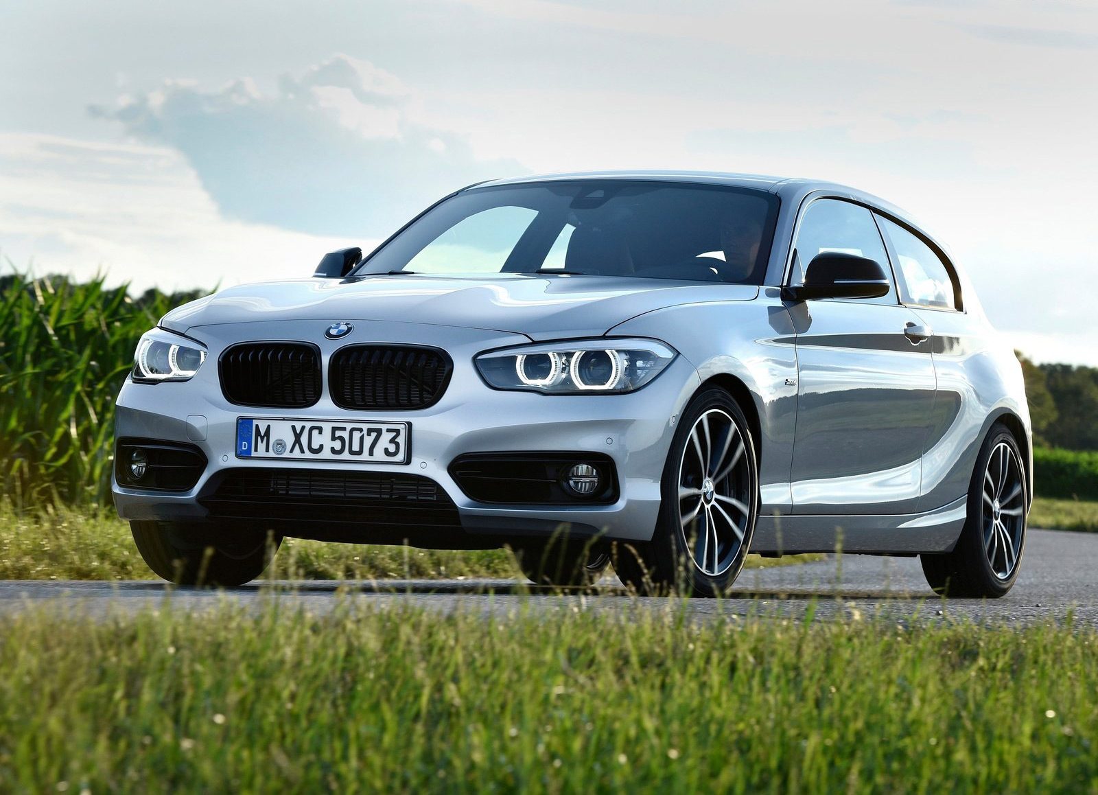 De nieuwe BMW 1-serie hatchback rijdt over een landweggetje.