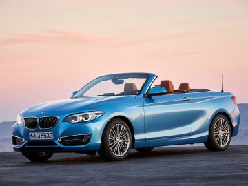 Een blauwe BMW 1 Serie cabriolet geparkeerd op de stoep.