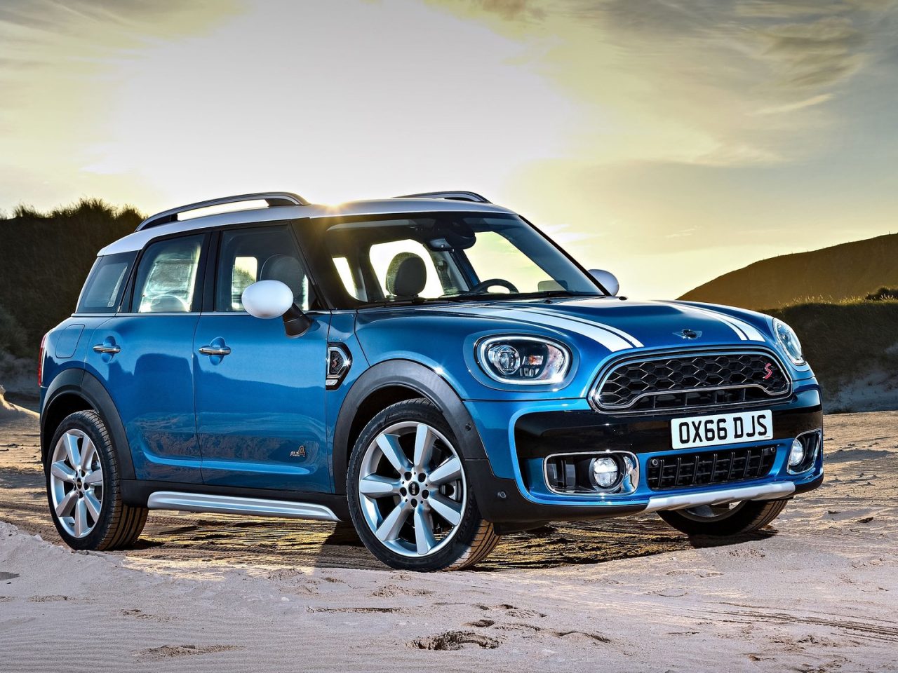 Op het strand staat de blauwe Mini Countryman met daktent geparkeerd.
