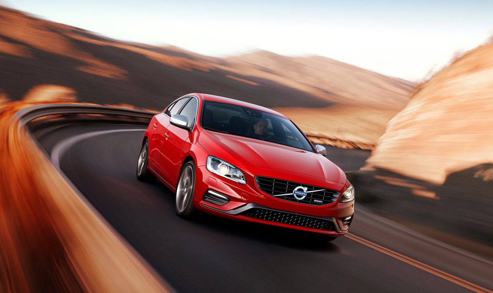 De verzekerde rode Volvo S60 rijdt over een bergweg.