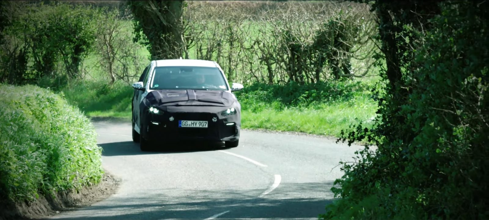 Een zwarte i30 N die over een landweg rijdt.