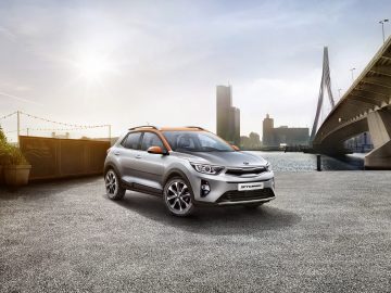 Voor een brug staat een Kia Stonic geparkeerd.