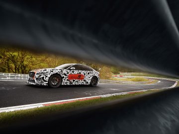 Een gecamoufleerde Jaguar XE SV Project 8 volbloed op een circuit.