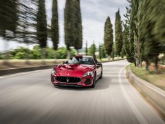 De Maserati GranTurismo rijdt over een landweggetje.