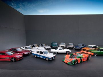 Een groep verschillend gekleurde Mazda-auto's in een kamer, vijftig jaar vierend met een rotatiemotor.