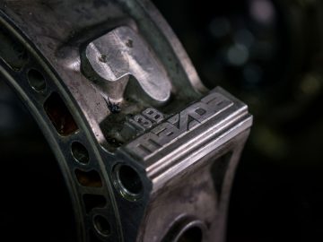 Een close-up van een stuk metaal met het Mazda-logo en "vijftig jaar rotatiemotor" erop.