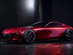De rode Mazda RX Vision-sportwagen wordt getoond in een donkere kamer.