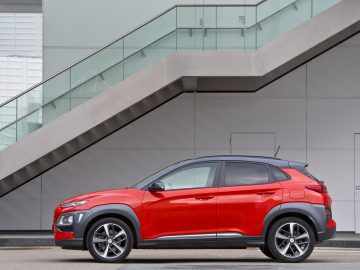 De Hyundai Kona staat voor een gebouw geparkeerd.