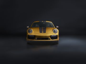 Op een donkere achtergrond is een gele Porsche 911 Turbo S afgebeeld.