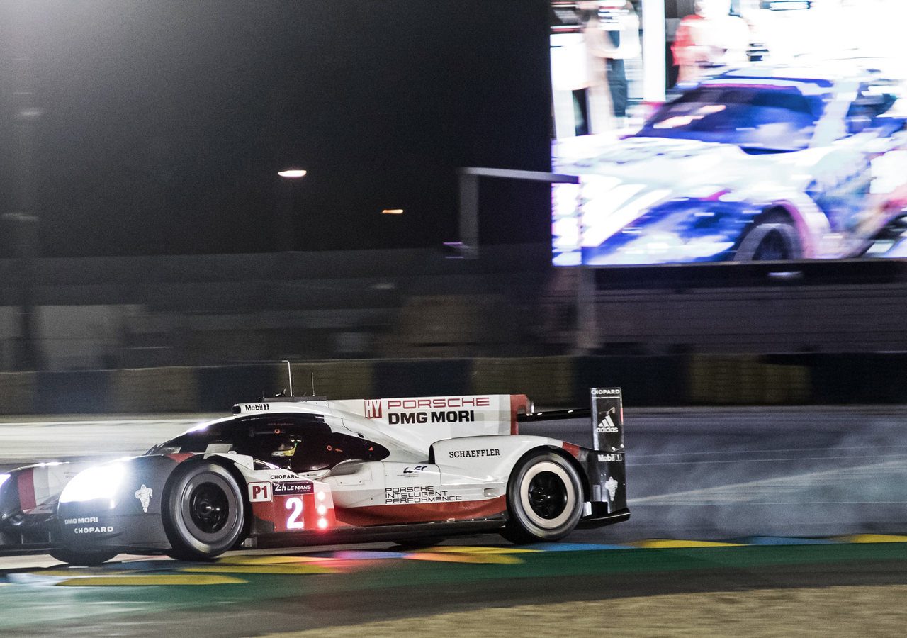 Een Porsche-racewagen op het circuit tijdens de 24 uur van Le Mans 's nachts.