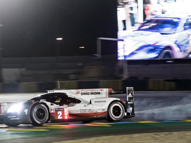 Een Porsche-racewagen op het circuit tijdens de 24 uur van Le Mans 's nachts.
