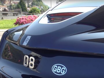 Er staat een Rolls-Royce langs de kant van de weg geparkeerd.