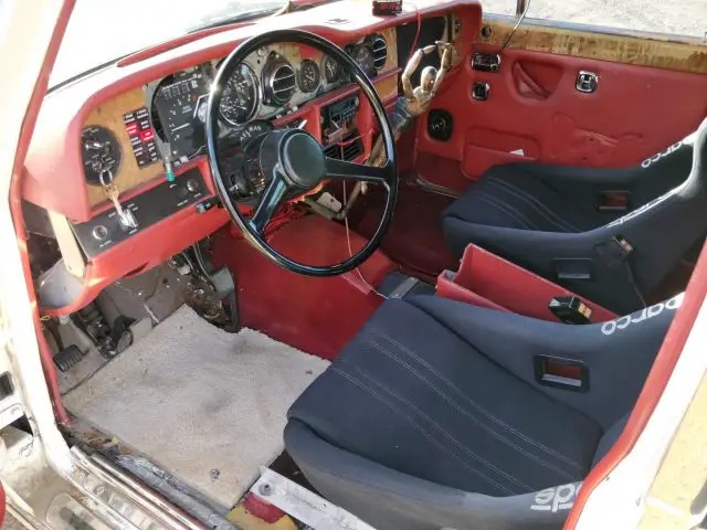 Het interieur van een rode Rolls-Royce met stuur en stuurwiel.