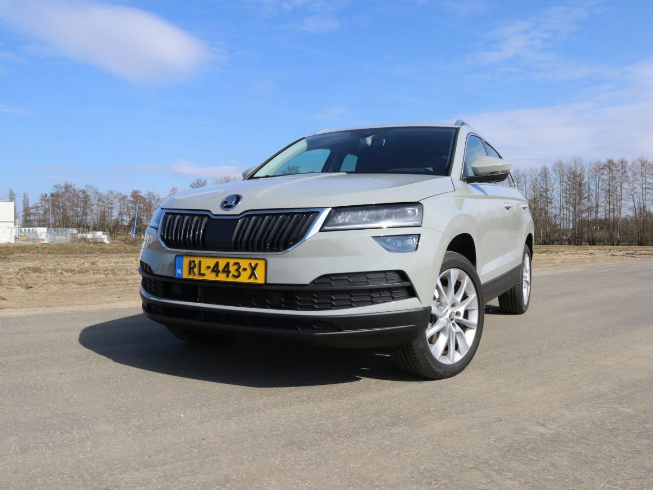Een grijze Skoda Karoq SUV staat geparkeerd op een onverharde weg.