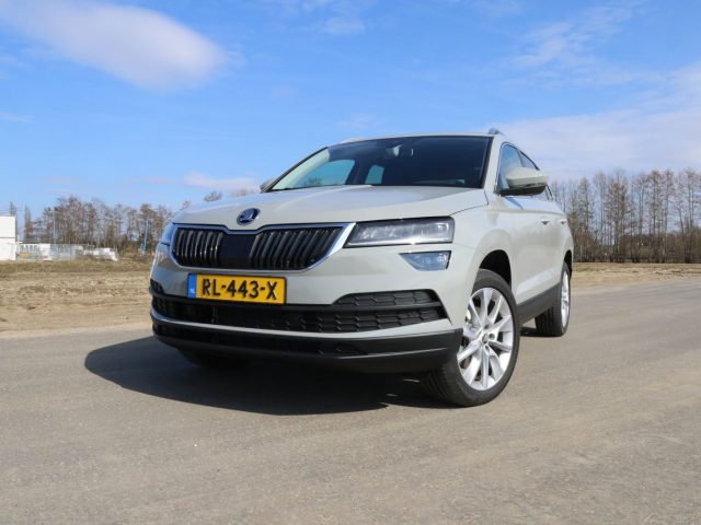 Een grijze Skoda Karoq SUV staat geparkeerd op een onverharde weg.