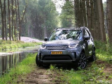 In een bosrijke omgeving staat een Land Rover Discovery geparkeerd.