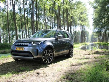 De Land Rover Discovery staat geparkeerd in een bosrijke omgeving.