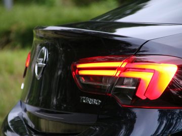 De achterkant van een zwarte Opel Insignia Grand Sport 1.5 Turbo met een rood achterlicht.