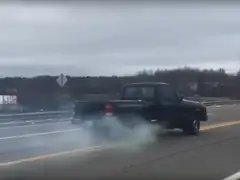 Een pick-up waar rook uit komt op de snelweg, gezien in een VIDEO die achteruit rijdt met 65 km/u.
