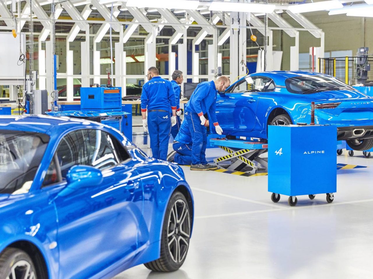 In een fabriek wordt gewerkt aan een blauwe Alpine A110-sportwagen.