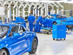 In een fabriek wordt gewerkt aan een blauwe Alpine A110-sportwagen.