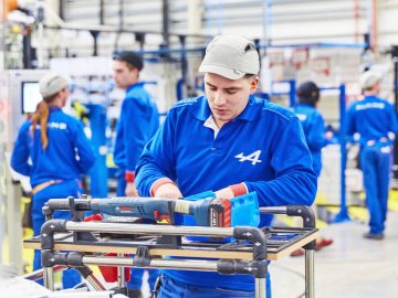 Een groep arbeiders werkt aan de nieuwe Alpine A110 in een fabriek.