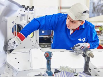 Een man aan het werk aan een Alpine A110 in een fabriek.