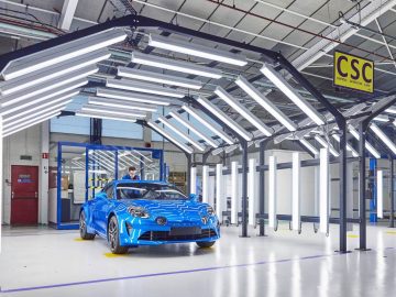 Een blauwe Alpine A110 staat geparkeerd in een fabriek.