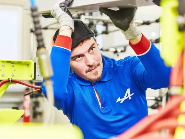 Een man die in een fabriek aan een Alpine A110-machine werkt.