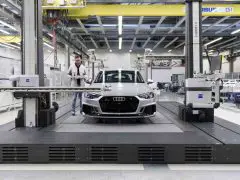 Een Audi RS4 ondergaat kwaliteitscontrole op een transportband in een fabriek.