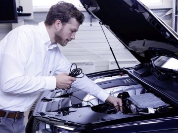 Een man die kwaliteitscontrole uitvoert op een Audi in een garage.