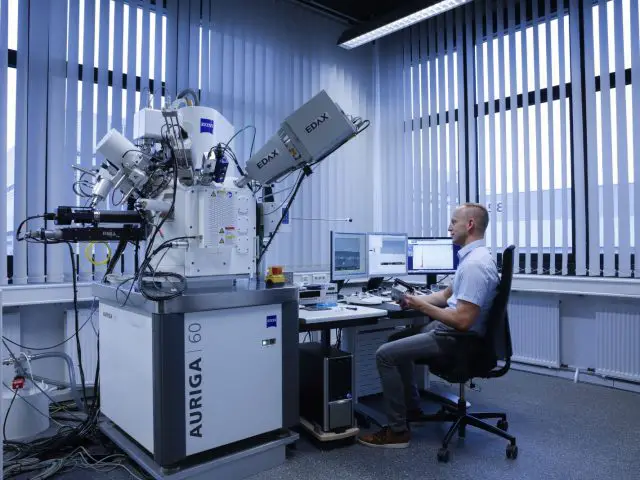 Een man zit aan een bureau in een laboratorium en voert kwaliteitscontroles uit voor Audi.