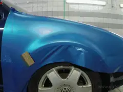 Een blauwe auto wordt in een garage gewrapped.