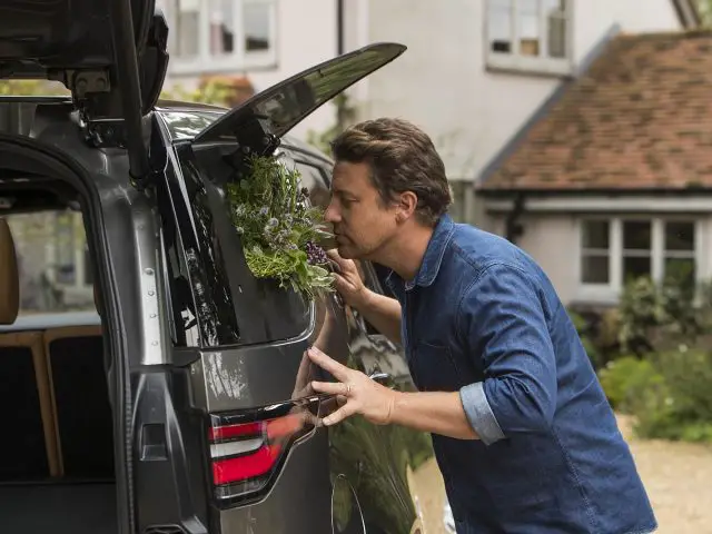 Een man die de kofferbak van een Land Rover Discovery opent.