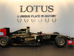 Een Lotus F1-auto is te koop en staat geparkeerd voor een muur.