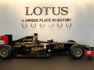 Een Lotus F1-auto is te koop en staat geparkeerd voor een muur.
